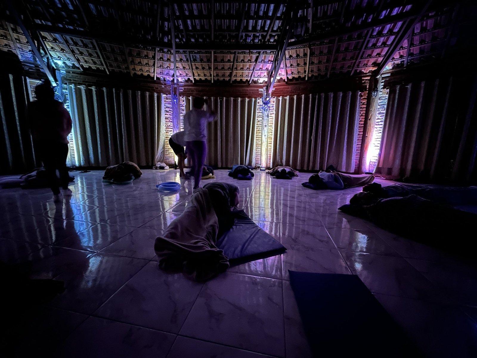 Participantes deitados em relaxamento na sala da imersão, em luz roxa